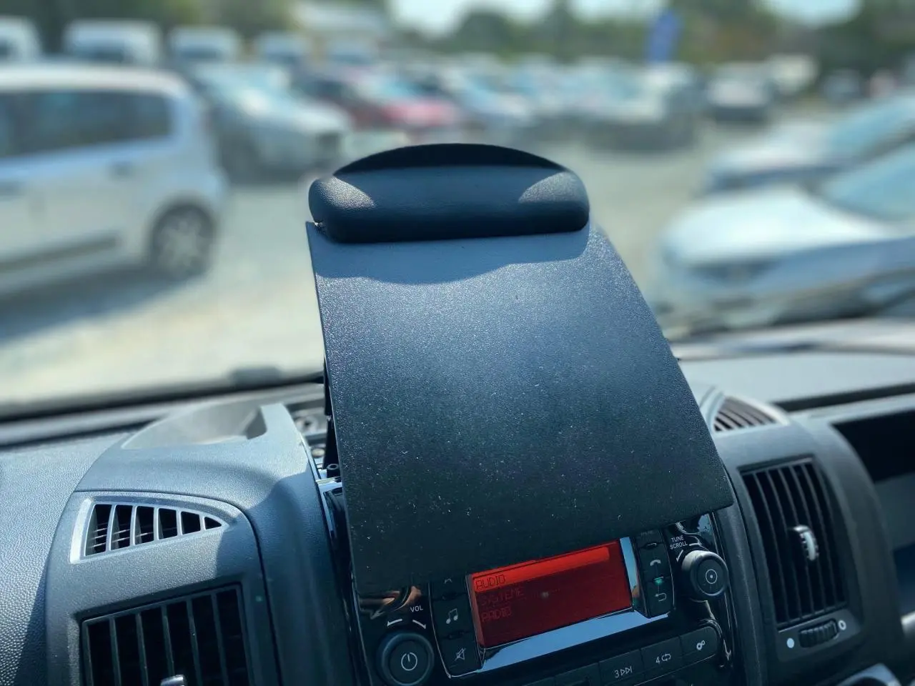 Vue rapprochée du tableau de bord noir du Citroën Jumper 2023 avec écran radio rouge et aérateurs latéraux.