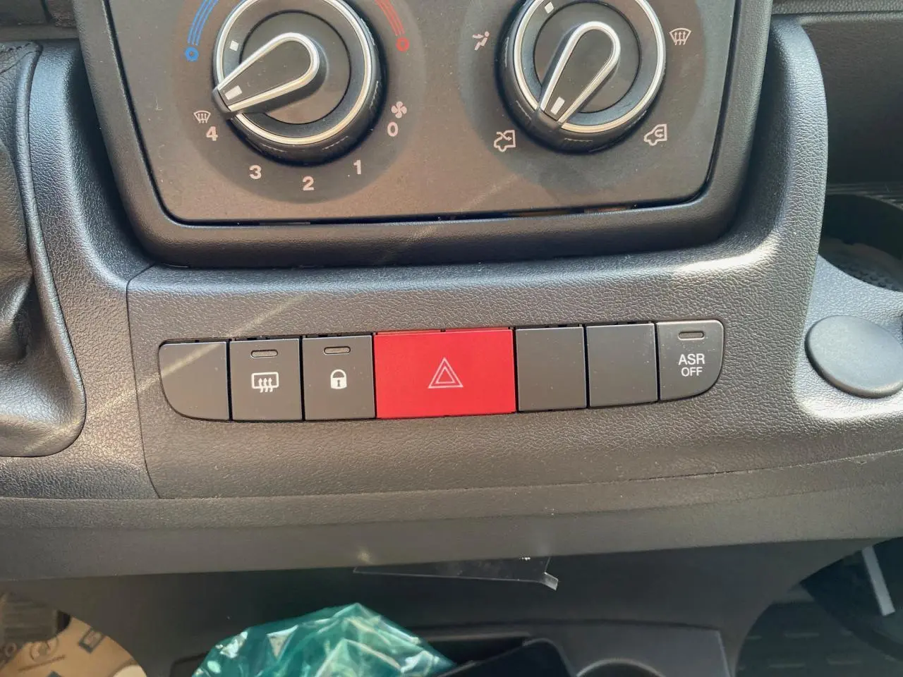 Gros plan sur la console centrale du Citroën Jumper blanc 2023 montrant les commandes de climatisation et boutons d'alerte et verrouillage.