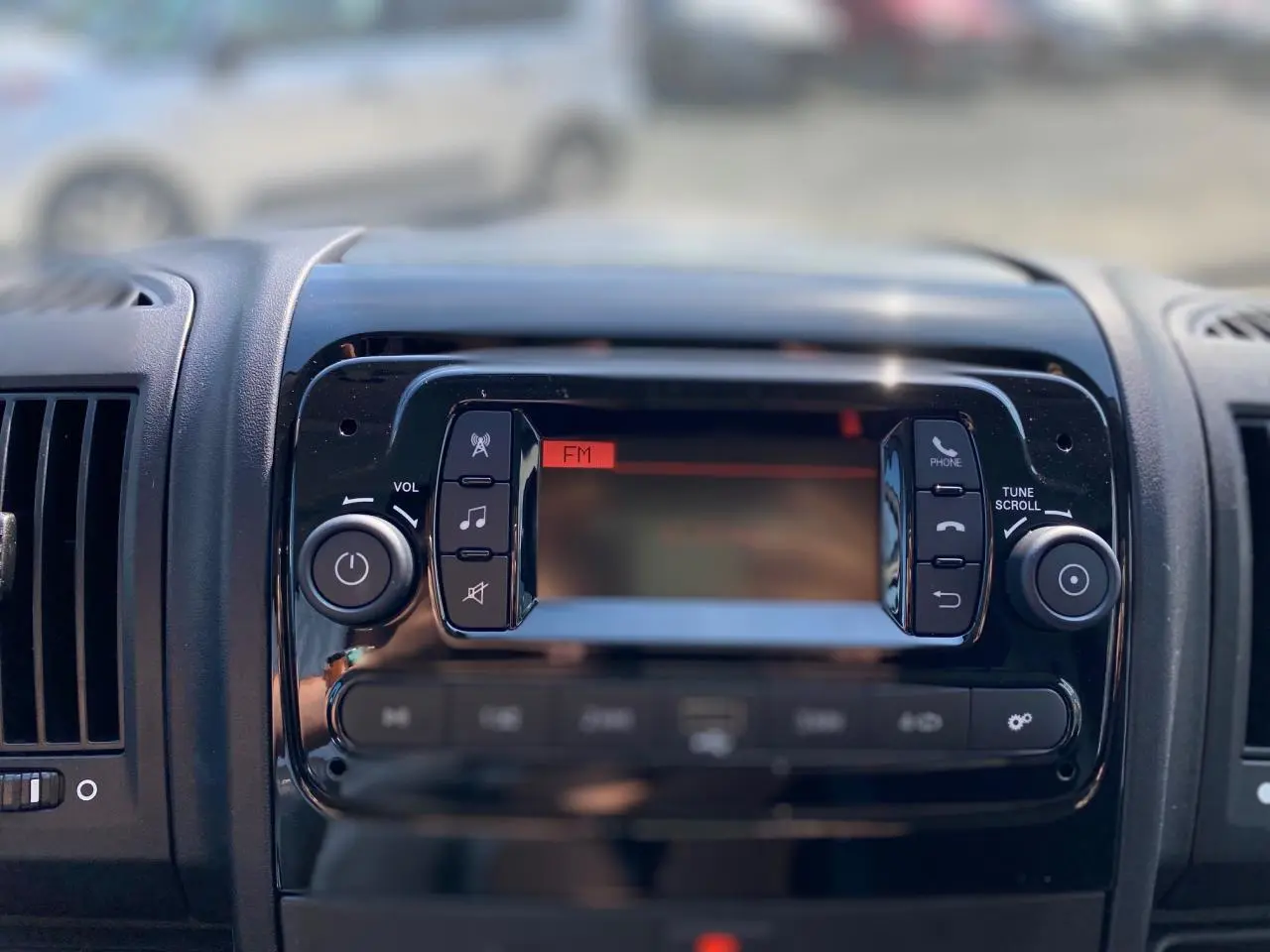 Vue rapprochée de la console centrale noire avec radio FM du Citroën Jumper 2023, intérieur moderne.