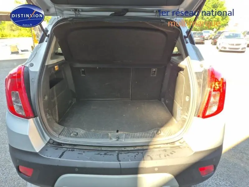 Coffre ouvert vu de l'arrière d'un Opel Mokka gris Astéroïde avec feux arrière rouges visibles.