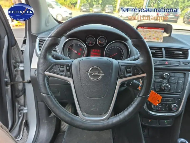 Vue intérieure centrée sur le volant cuir noir de l'Opel Mokka gris Astéroïde avec tableau de bord et écran GPS visible.