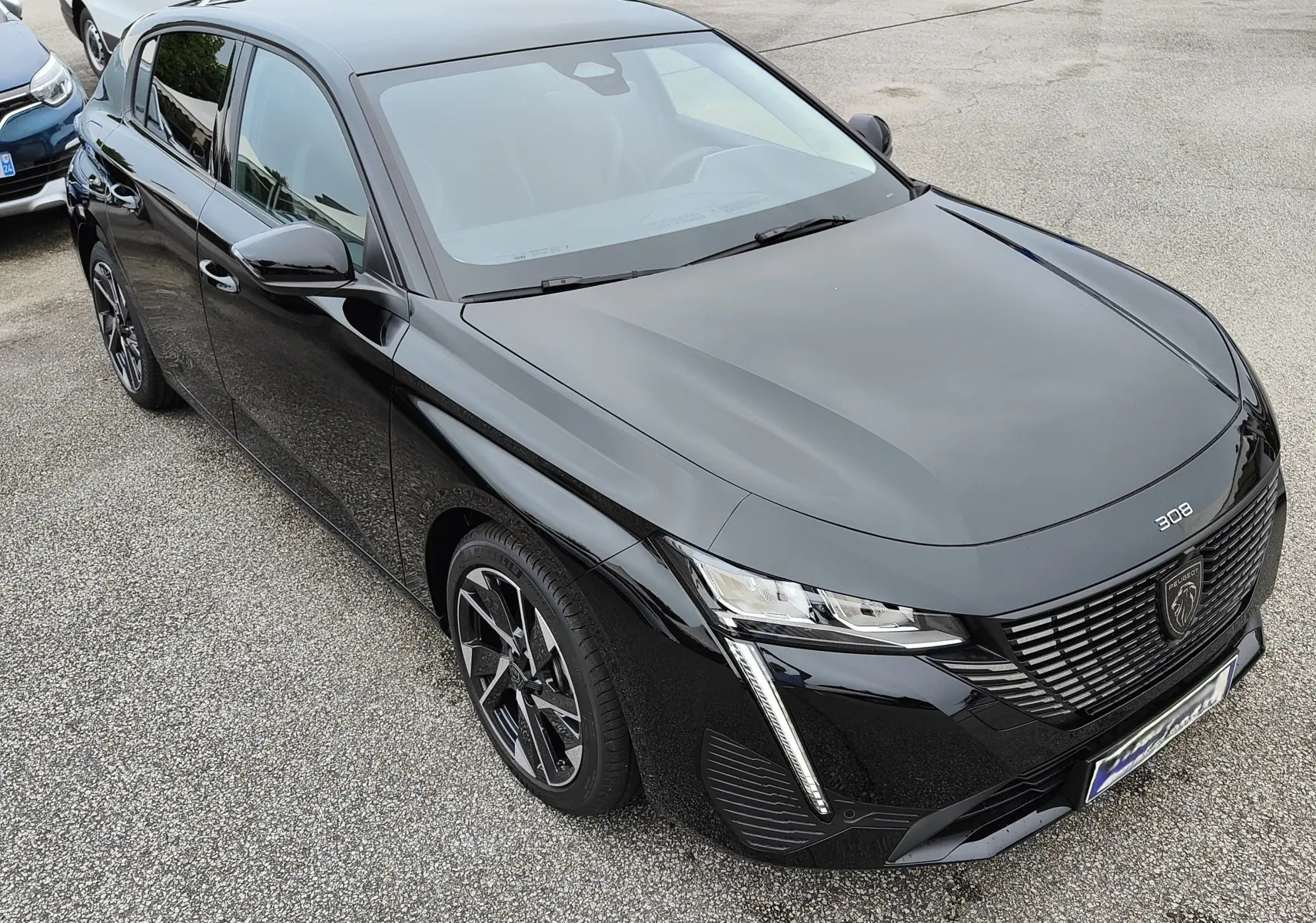Peugeot 308 PureTech 130 Allure Pack noire vue en 3/4 avant droit, avec calandre et feux LED distinctifs.