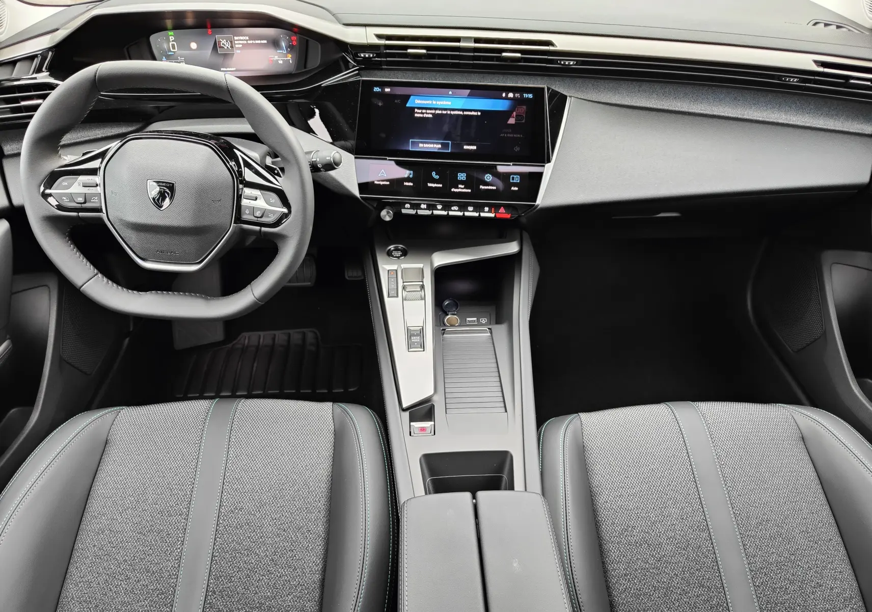 Vue intérieure de face du poste de conduite de la Peugeot 308 PureTech 130 Allure Pack 2023, avec tableau de bord numérique et écran tactile central.