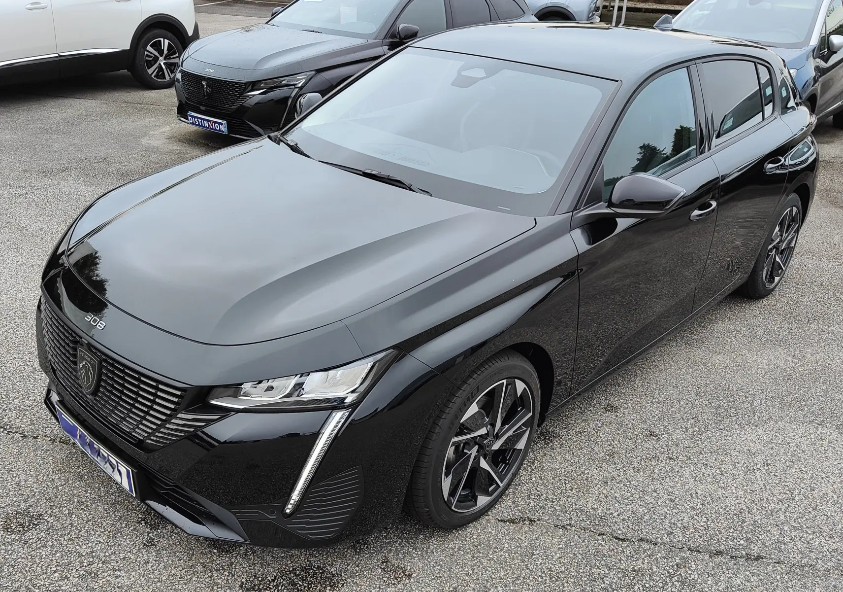 Peugeot 308 PureTech 130 Allure Pack noire vue en 3/4 avant droit, avec jantes bi-ton et feux LED distinctifs.