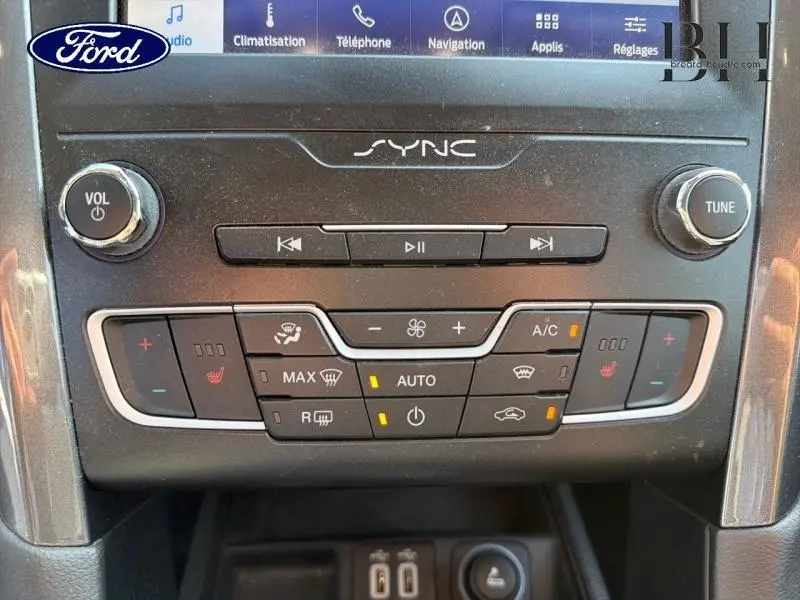 Gros plan sur la console centrale de la Ford Mondeo gris Premium, montrant les commandes climatisation et audio SYNC.