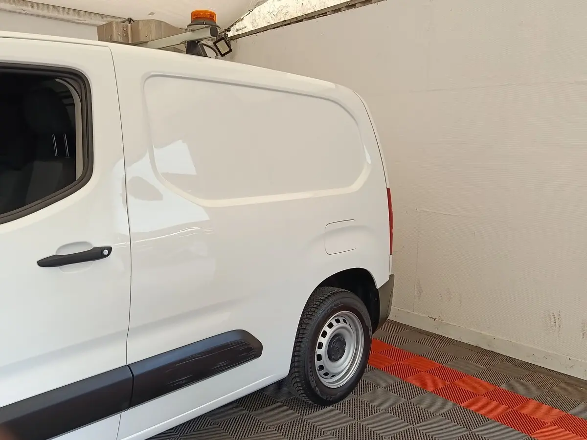 Vue latérale droite arrière d’un utilitaire Peugeot Partner blanc avec porte latérale pleine et jante acier.