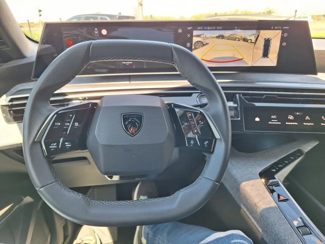 Vue intérieure centrée sur le volant cuir du Peugeot 3008 Hybrid 2025 avec cockpit numérique et affichage caméra de recul.