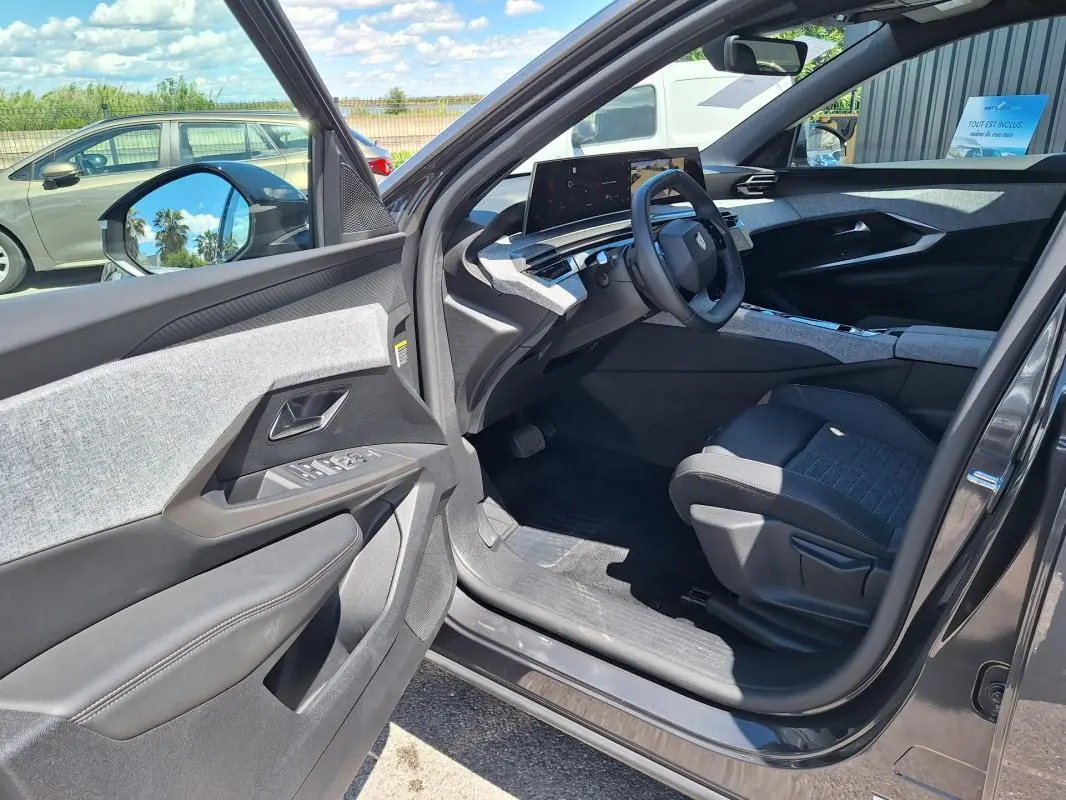 Vue intérieure côté conducteur du Peugeot 3008 Hybrid gris foncé, mettant en valeur le cockpit numérique et les finitions modernes.