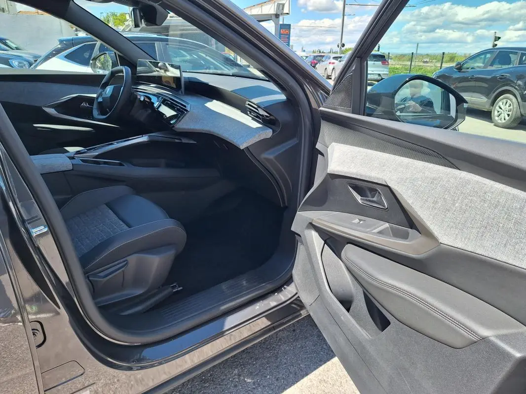 Intérieur côté passager du Peugeot 3008 Hybrid 2025 gris foncé, mettant en valeur la planche de bord et les finitions tissu et cuir.
