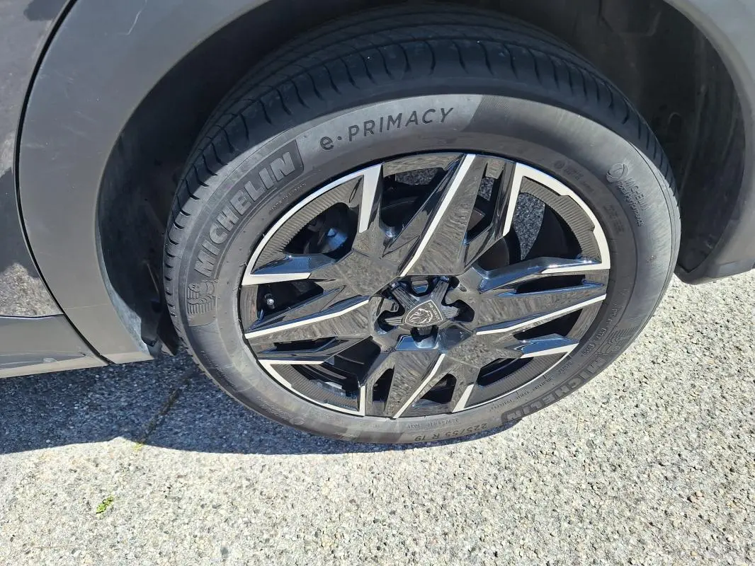 Gros plan sur la jante alliage 19 pouces noire et argentée du côté avant gauche du Peugeot 3008 Hybrid gris foncé.