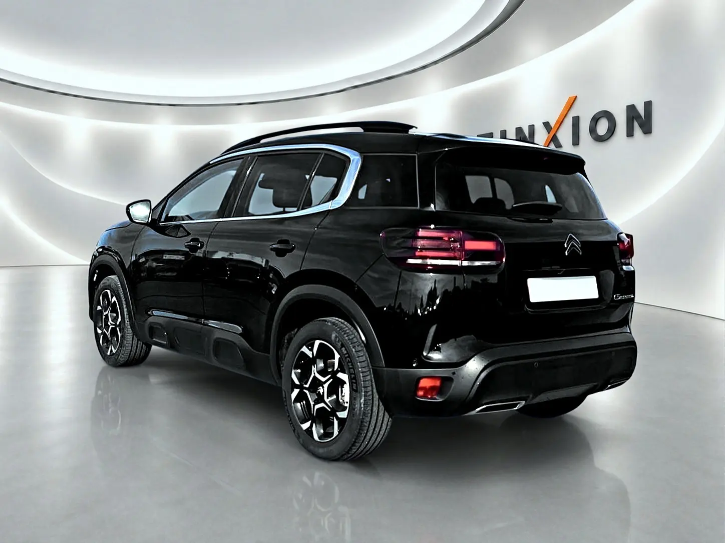 Vue 3/4 arrière droite du Citroën C5 Aircross noir 2025 avec jantes alu et barres de toit visibles.