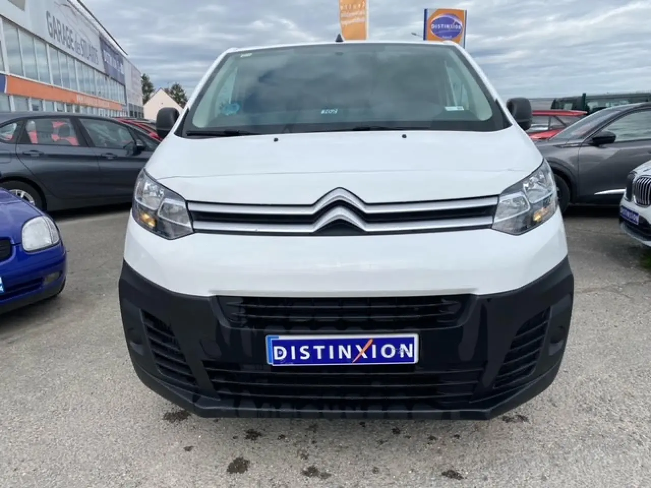 Vue frontale d’un utilitaire Citroën Jumpy blanc avec pare-chocs noir et plaque Distinxion visible.
