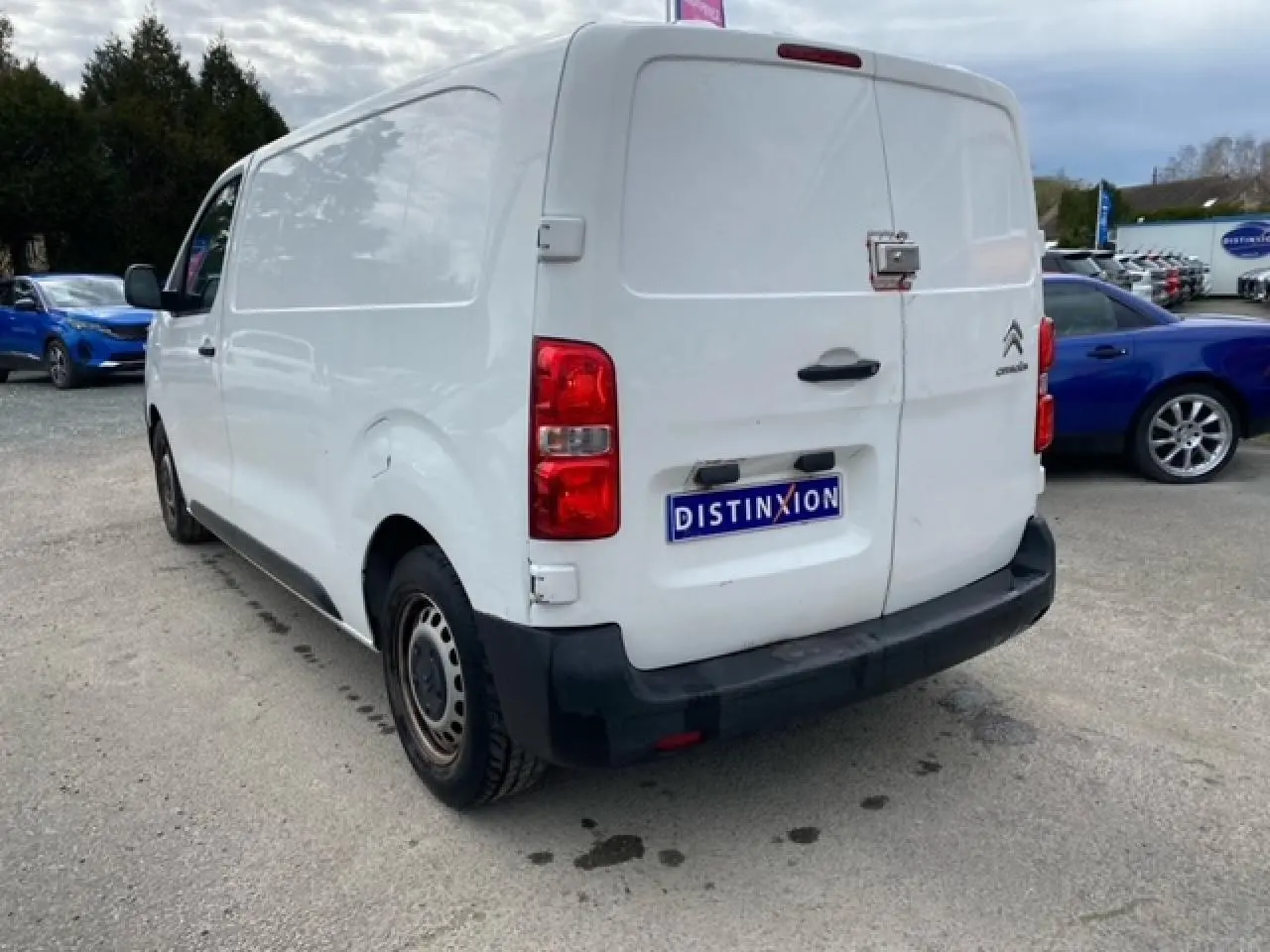 Vue 3/4 arrière droite d'un utilitaire Citroën Jumpy blanc avec portes arrière battantes et pare-chocs noir.