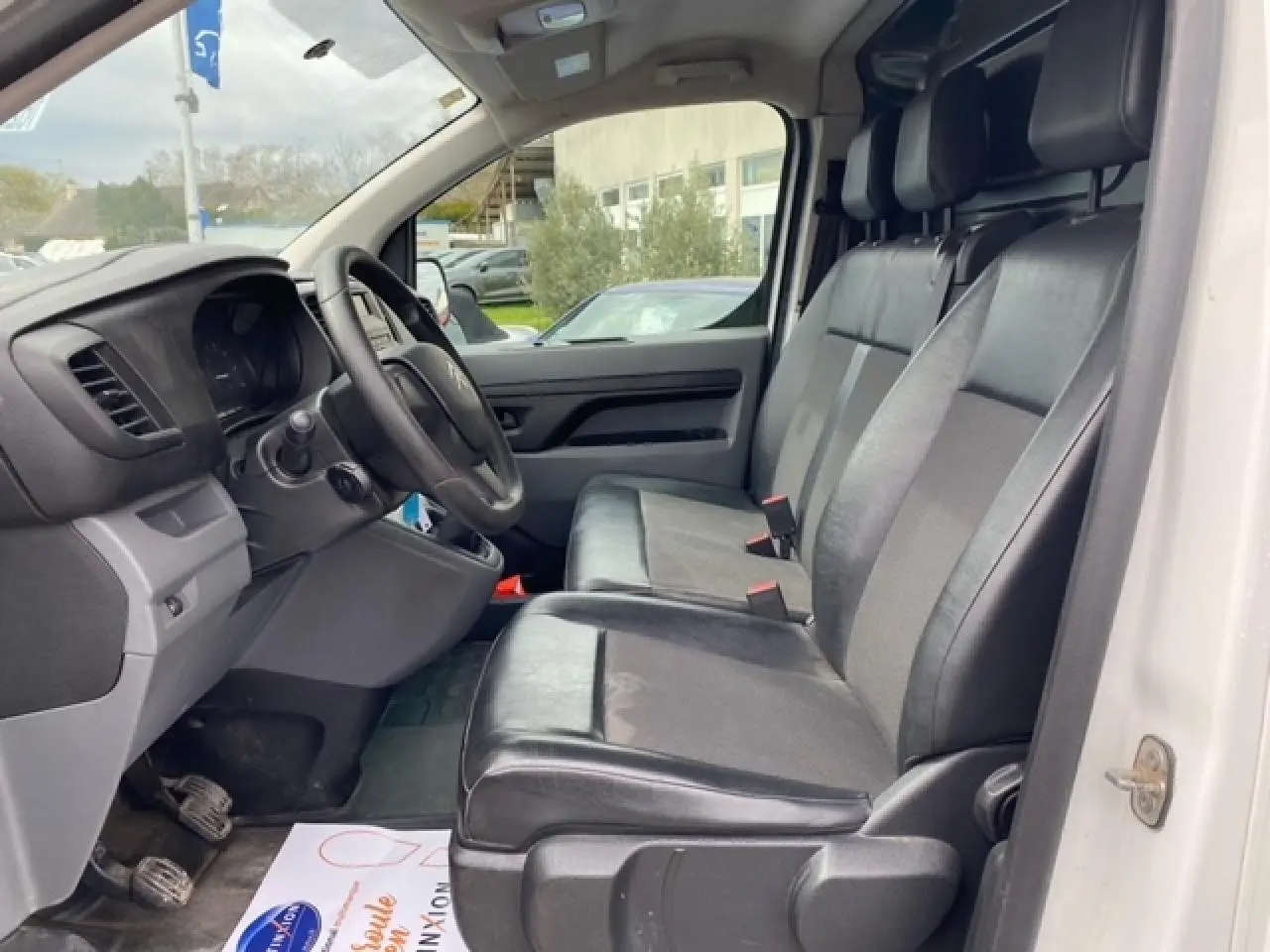 Vue intérieure côté conducteur du Citroën Jumpy blanc 2019, sièges mixtes TEP/tissu et tableau de bord simple.