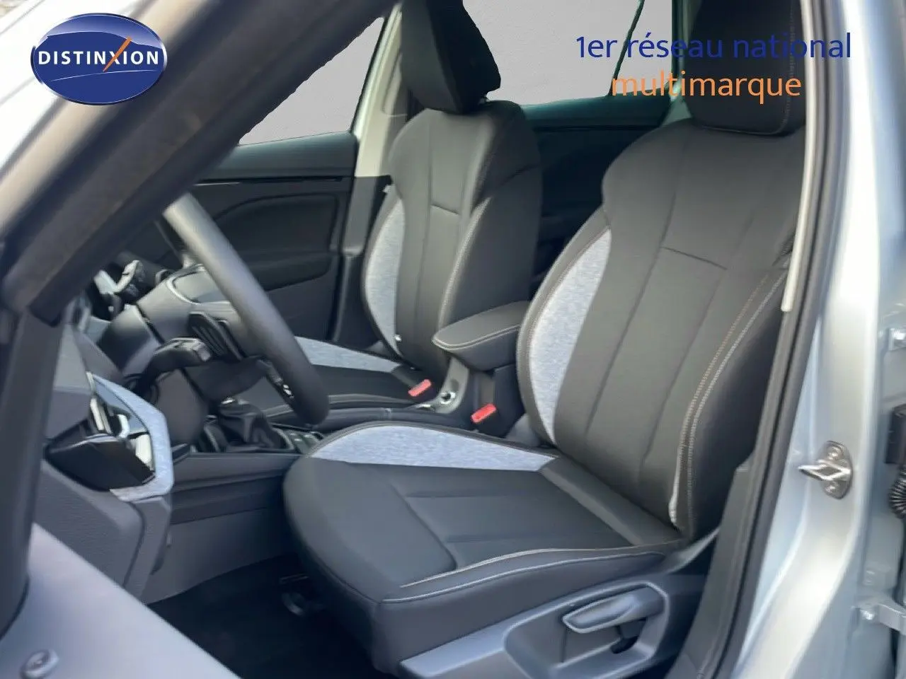 Intérieur de la Skoda Kamiq 2025, vue côté conducteur, sièges tissu gris clair et noir avec surpiqûres contrastées.