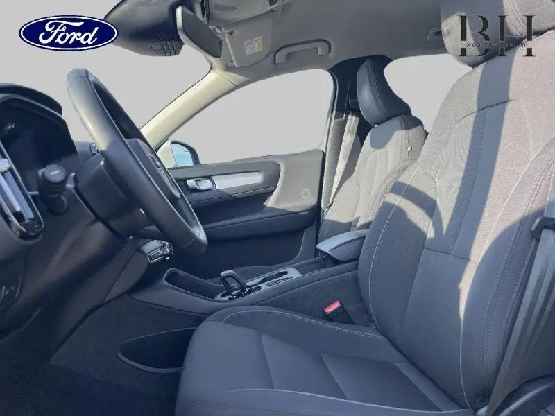 Vue intérieure côté conducteur du Volvo XC40 T5 Recharge 2021, sièges tissu gris et volant cuir noir.