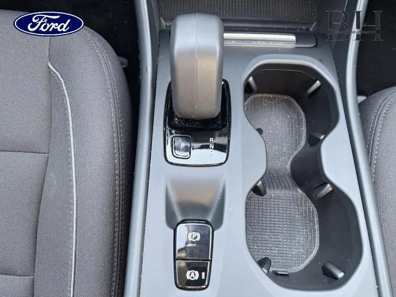 Vue plongeante sur la console centrale avec levier de vitesses et porte-gobelets d’un Volvo XC40 gris Glacier hybride rechargeable.