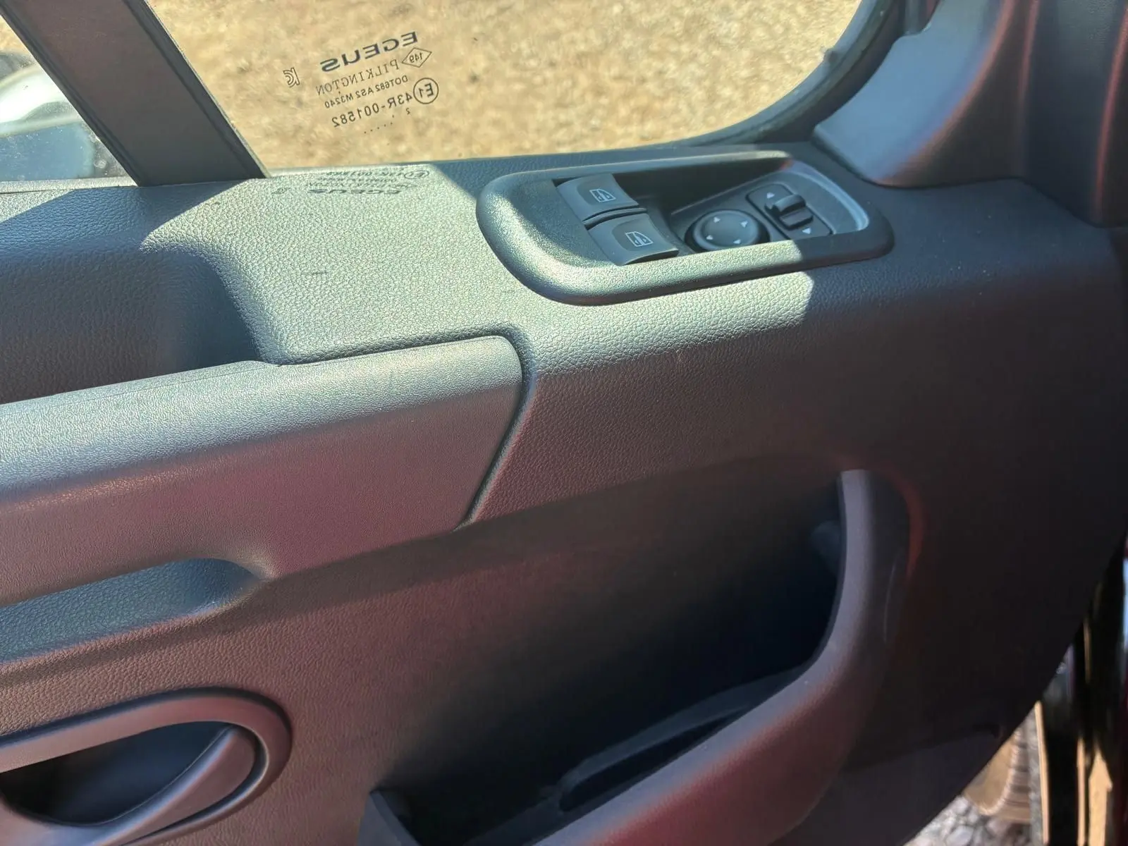 Gros plan sur la commande des vitres électriques côté gauche de la porte intérieure du Renault Master gris 2023.