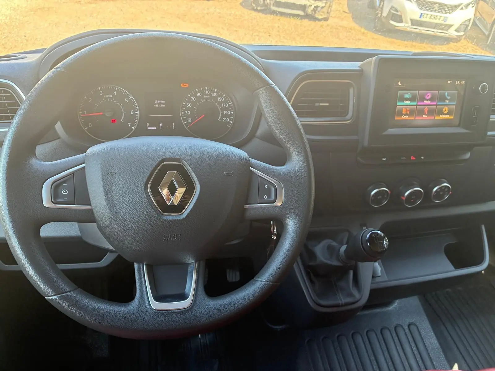 Vue intérieure centrée sur le volant Renault et le tableau de bord avec écran tactile et levier de vitesses manuel.
