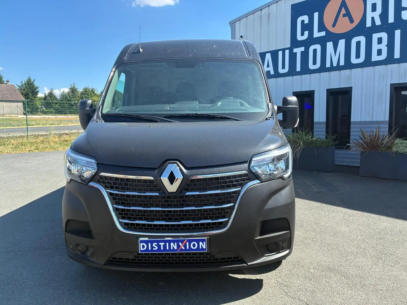 Vue avant d’un Renault Master gris 2023 avec calandre chromée et logo Renault bien visible, stationné devant un bâtiment.