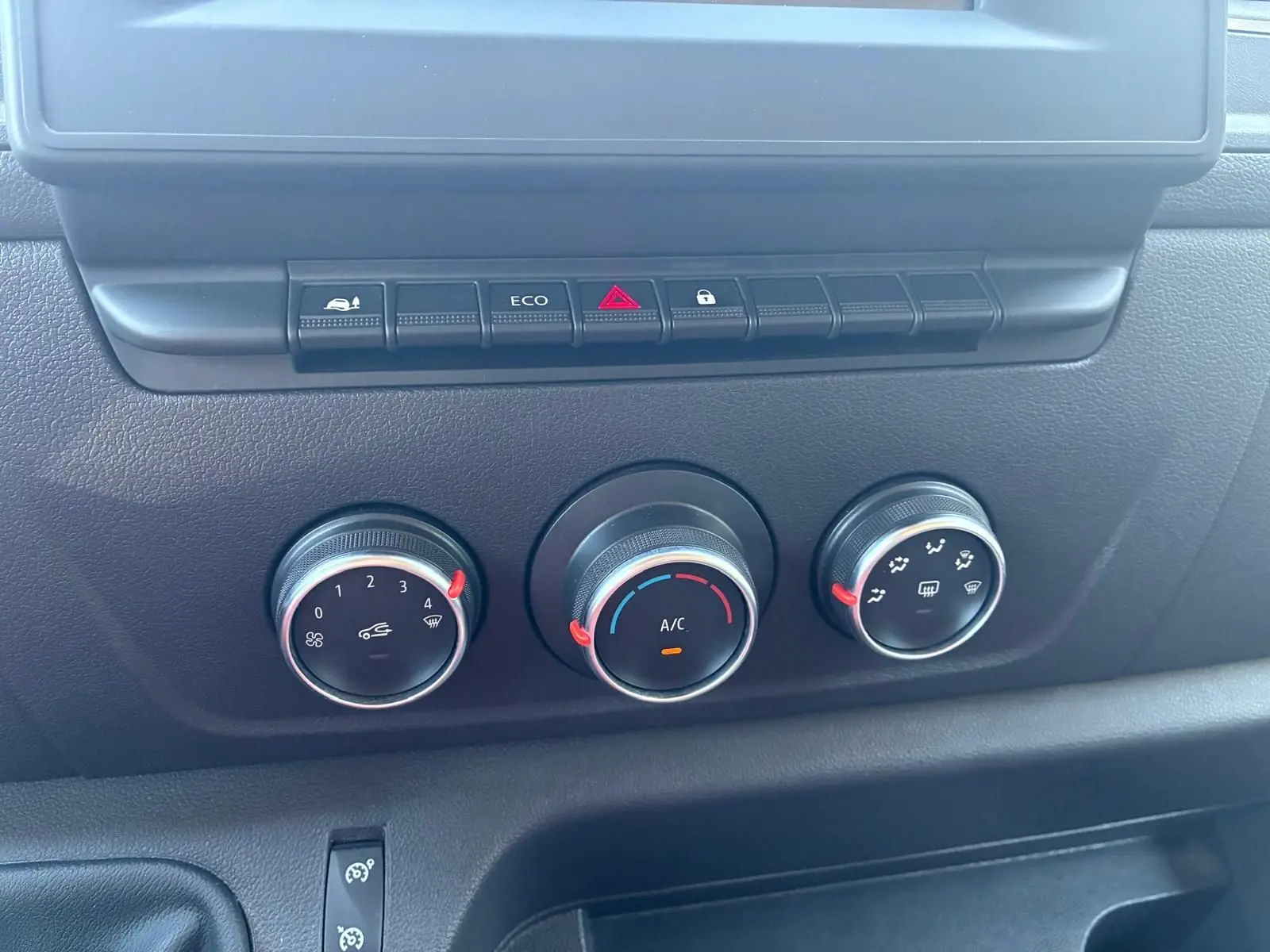 Gros plan sur les commandes de climatisation et les boutons de fonction du tableau de bord noir du Renault Master gris 2023.