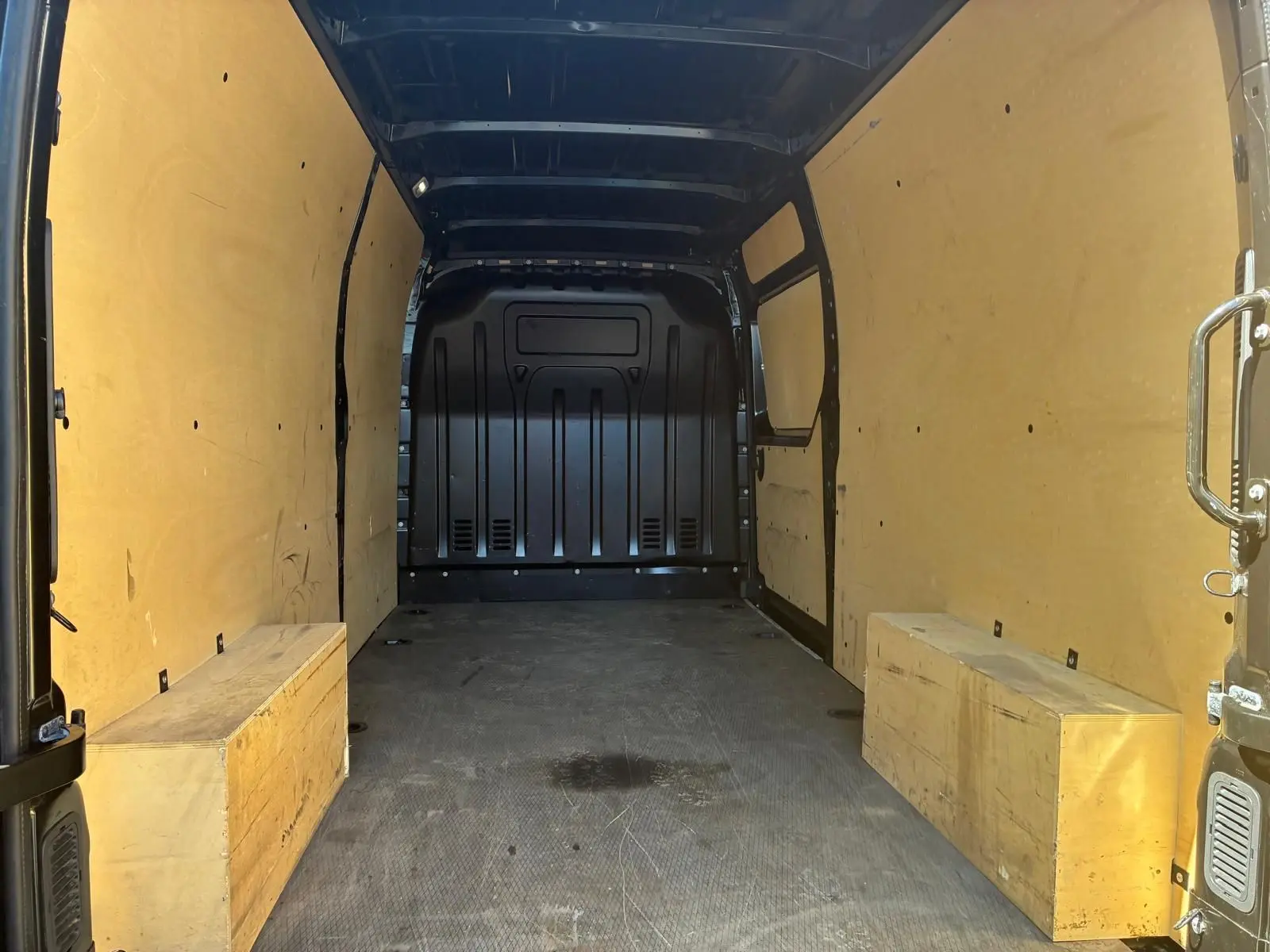 Vue intérieure arrière du Renault Master gris 2023, montrant l'espace de chargement avec parois et coffres en bois clair.