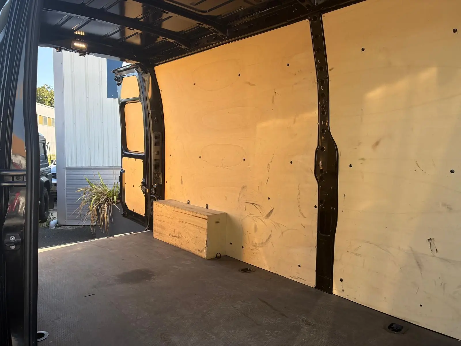 Vue intérieure arrière du Renault Master gris 2023, montrant l'espace de chargement avec parois en bois et porte ouverte côté gauche.