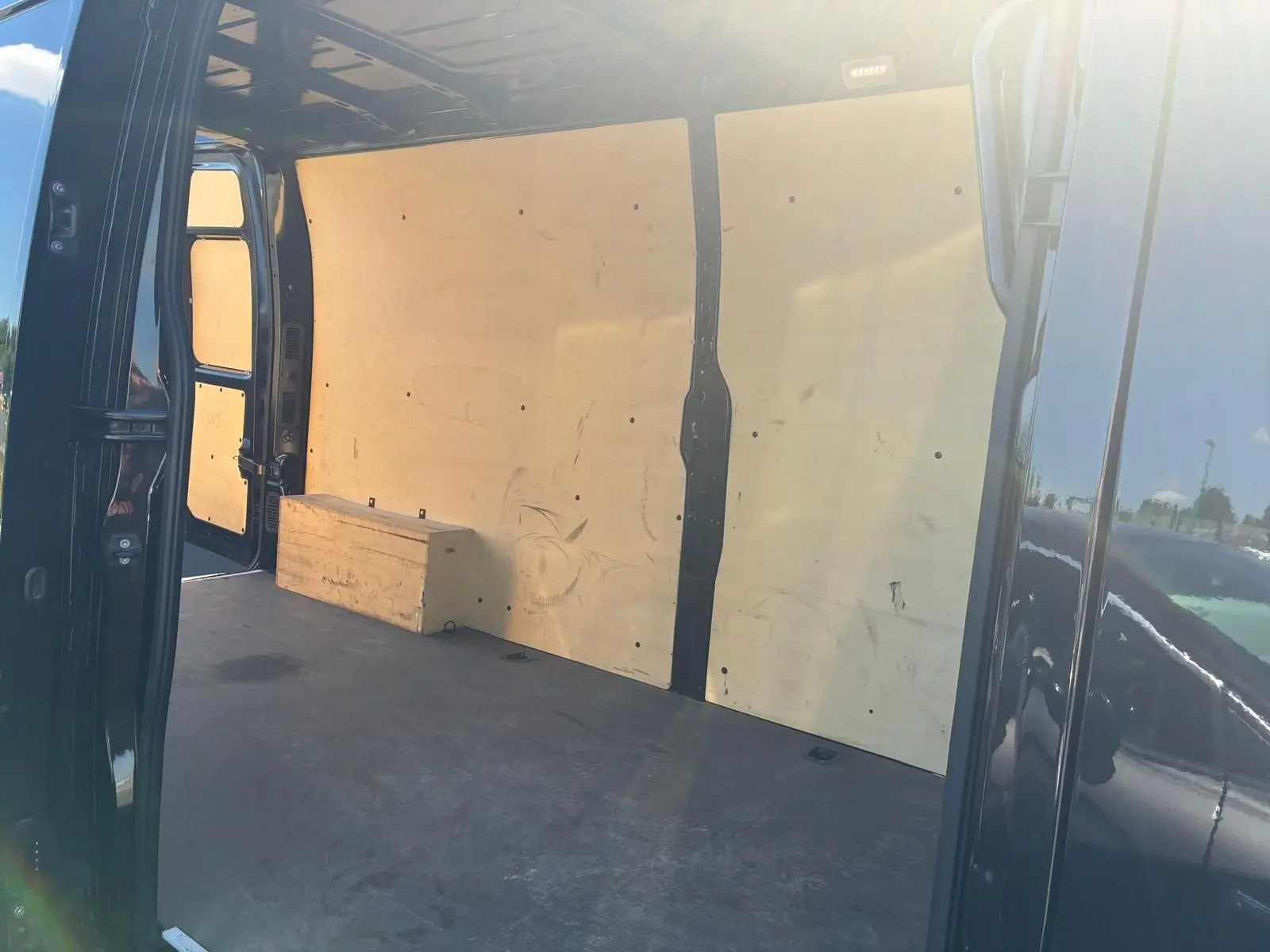 Vue intérieure côté droit du coffre d’un Renault Master gris 2023 avec parois en bois et plancher noir.