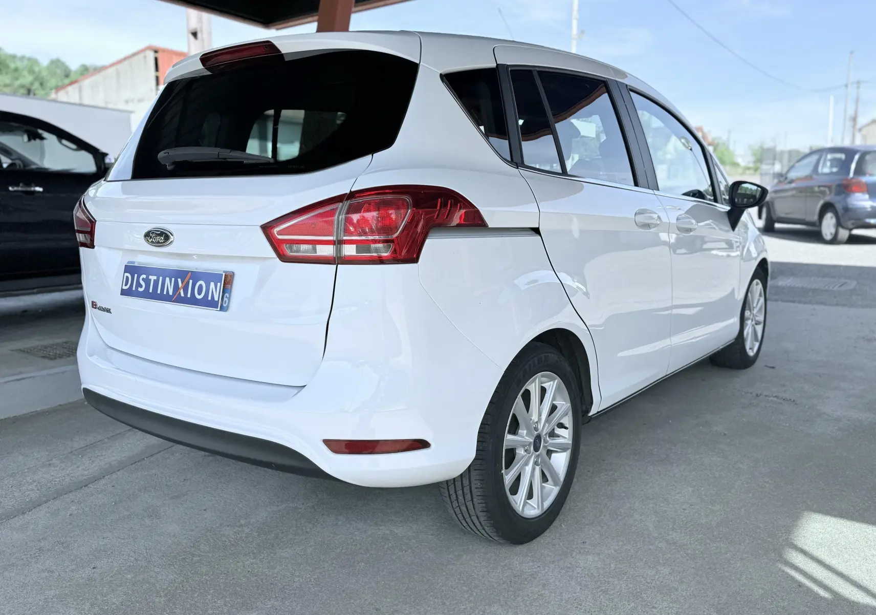 Vue 3/4 arrière droite d'une Ford B-MAX blanche de 2017 avec feux arrière rouges et jantes alliage.