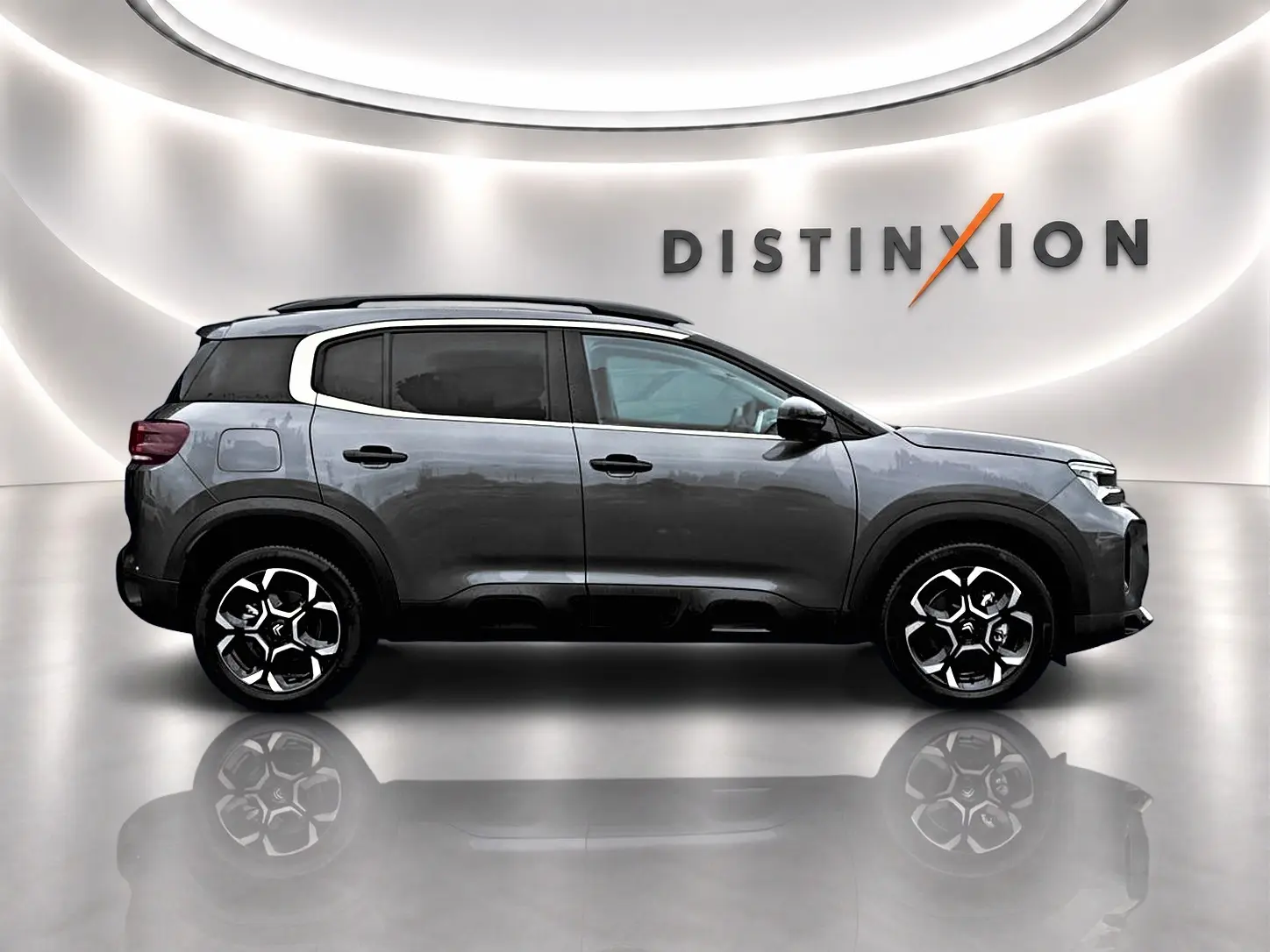 Profil droit du Citroën C5 Aircross gris platinium avec jantes alu et barres de toit, en studio lumineux avec logo Distinxion.