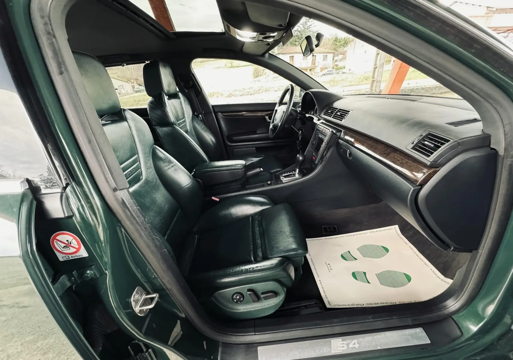 Intérieur noir cuir de l'Audi S4 Avant 2004 vu côté conducteur avec tableau de bord et sièges sport.