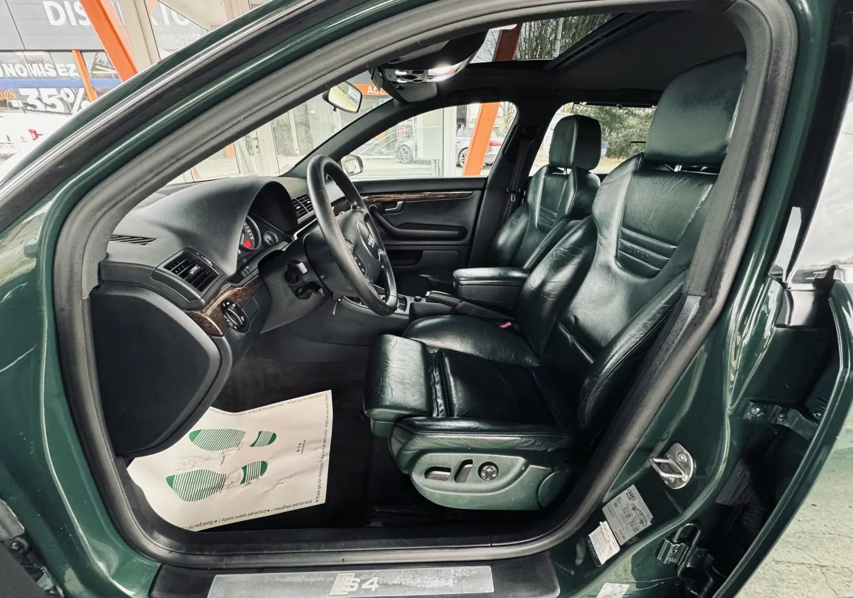 Vue côté gauche de l'intérieur vert foncé cuir de l'Audi S4 Avant 2004 avec sièges électriques et volant multifonction.