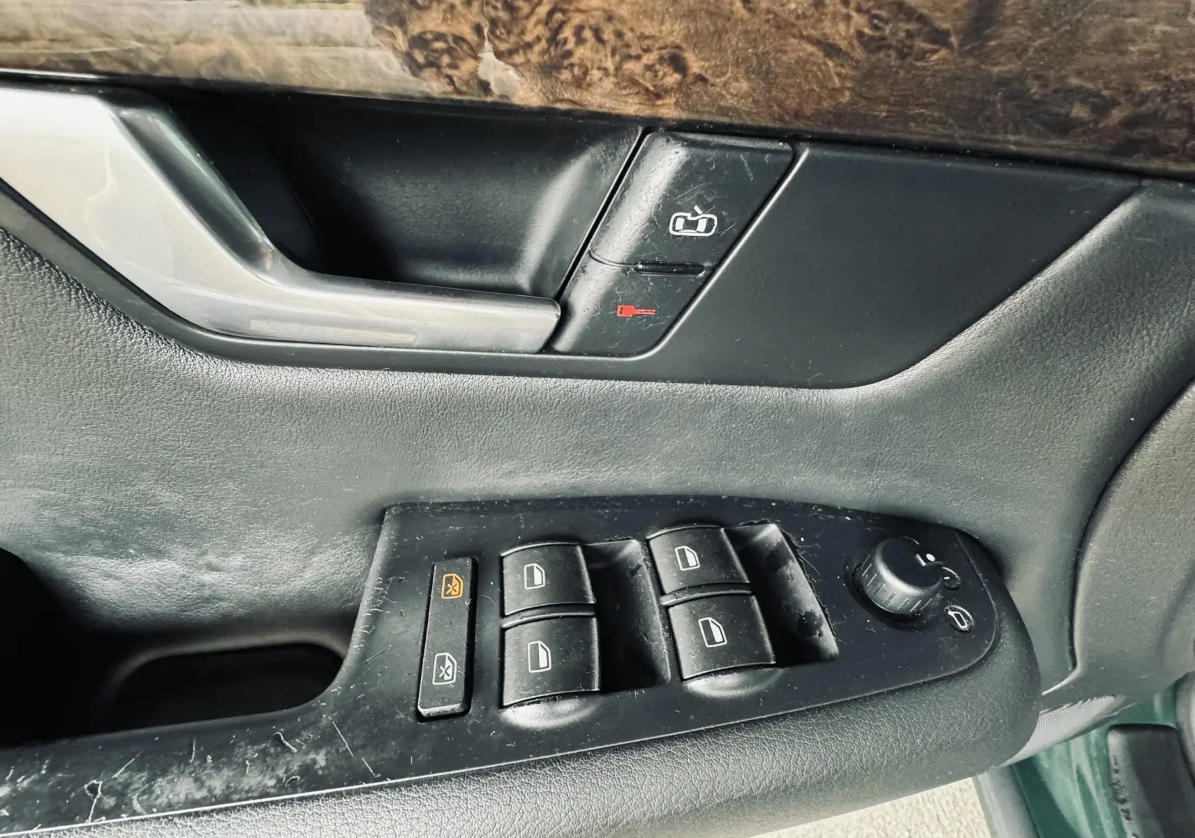 Gros plan sur les commandes de lève-vitres et serrure de la portière côté conducteur d'une Audi S4 Avant verte.