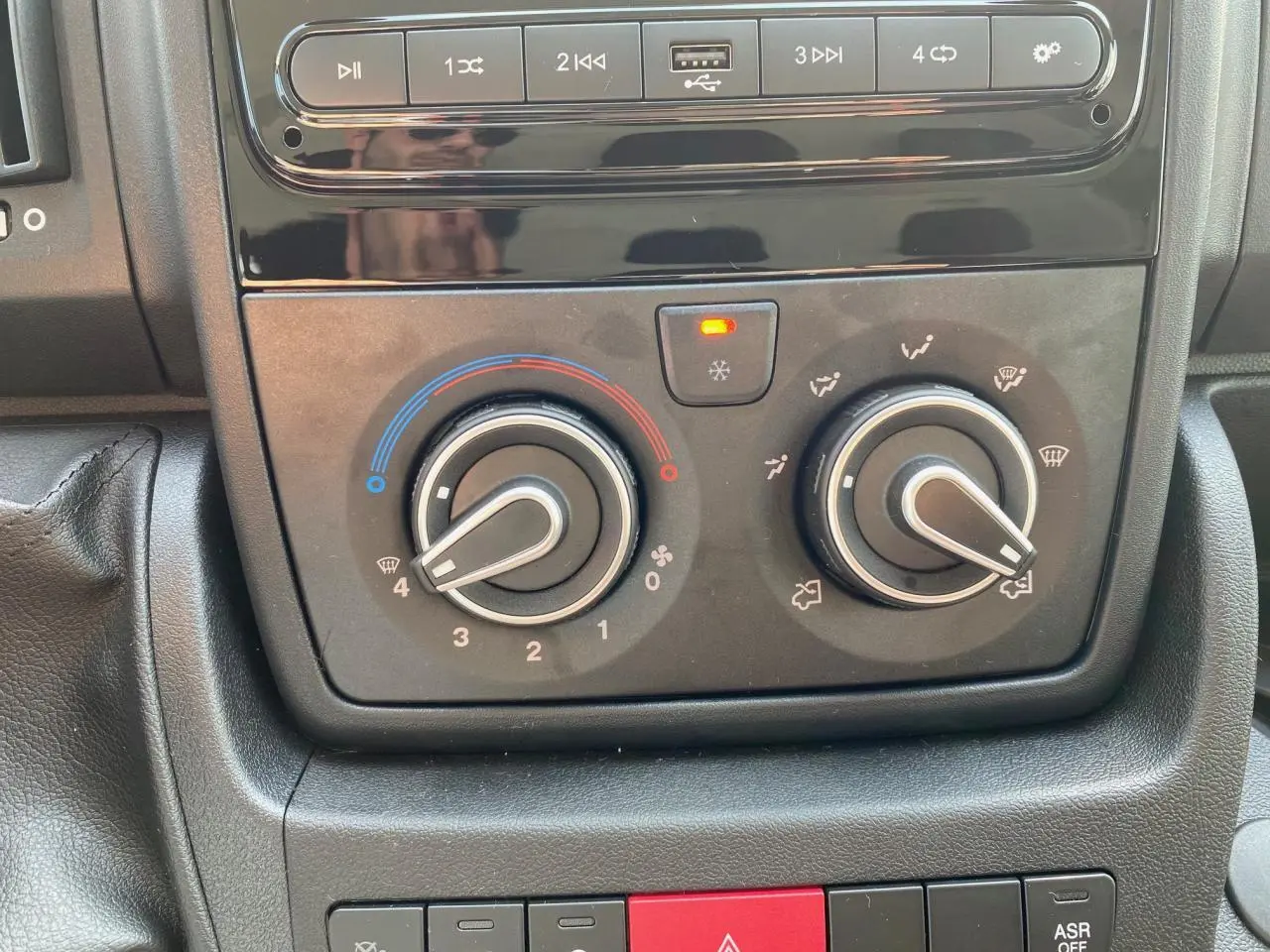 Gros plan sur les commandes de climatisation manuelle et audio du Peugeot Boxer Fourgon blanc 2023.