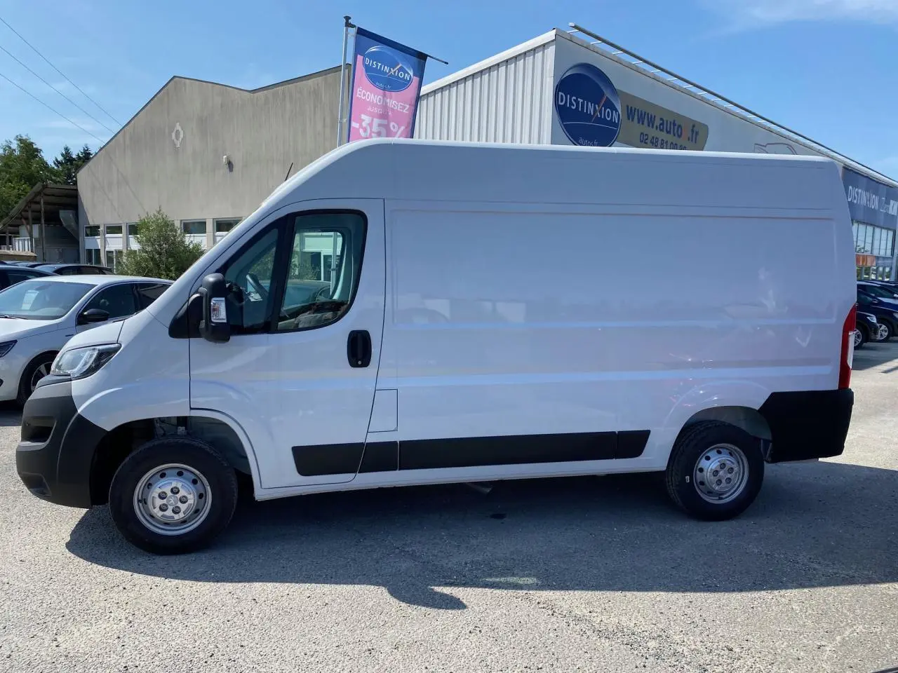 Vue latérale gauche d'un Peugeot Boxer Fourgon blanc 2023 avec porte latérale coulissante et protections noires.