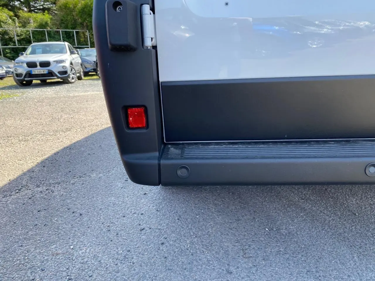 Gros plan sur le bas du hayon arrière blanc du Peugeot Boxer Fourgon avec radar de recul visible.