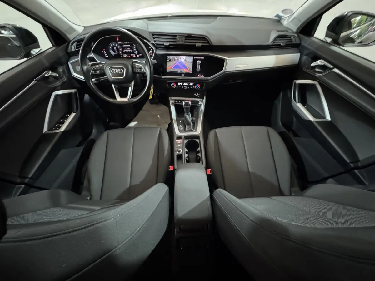 Vue intérieure avant de l'Audi Q3 noir 2022, tableau de bord digital et écran central avec caméra de recul affichée.