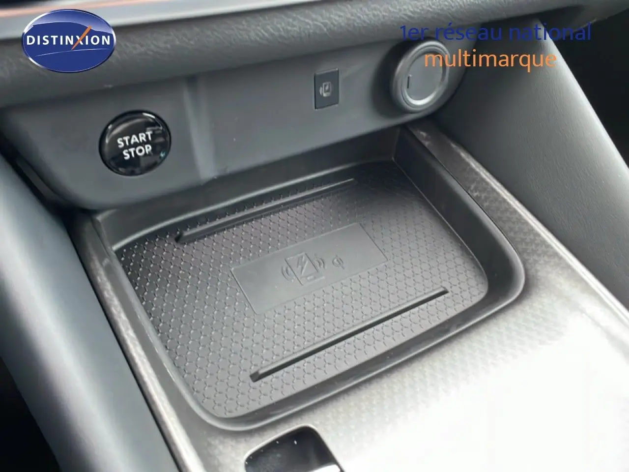 Gros plan sur la console centrale du Nissan Qashqai 2025, avec zone de charge sans fil et bouton start/stop visible.