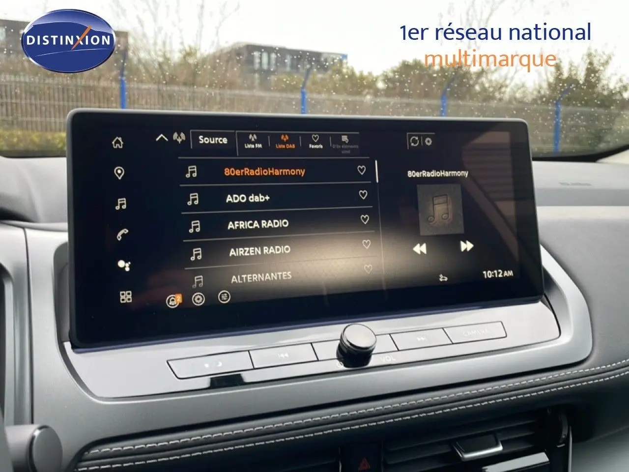 Vue intérieure centrée sur l'écran tactile multimédia du Nissan Qashqai blanc nacré 2025 affichant les stations radio.