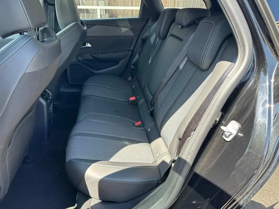 Vue intérieure côté arrière droit du Peugeot 308 SW Hybrid noir, montrant les sièges arrière en tissu et cuir avec ceinture de sécurité.