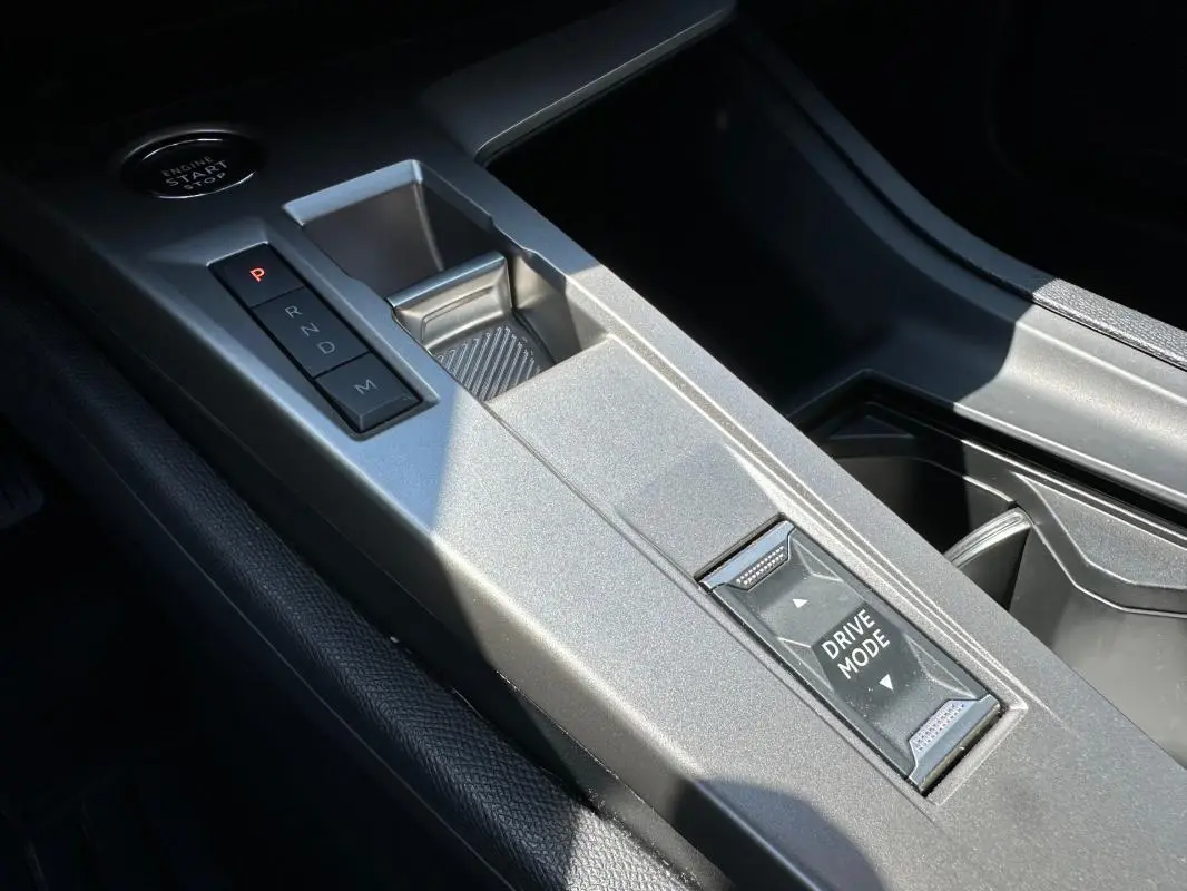 Gros plan sur la console centrale grise avec sélecteur de boîte auto et bouton Drive Mode du Peugeot 308 SW Hybrid 2025.