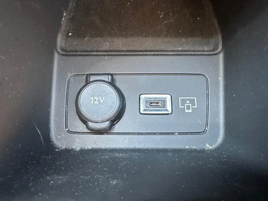 Gros plan sur la prise 12V et port USB-C dans l'habitacle noir du Peugeot 308 SW Hybrid 2025.