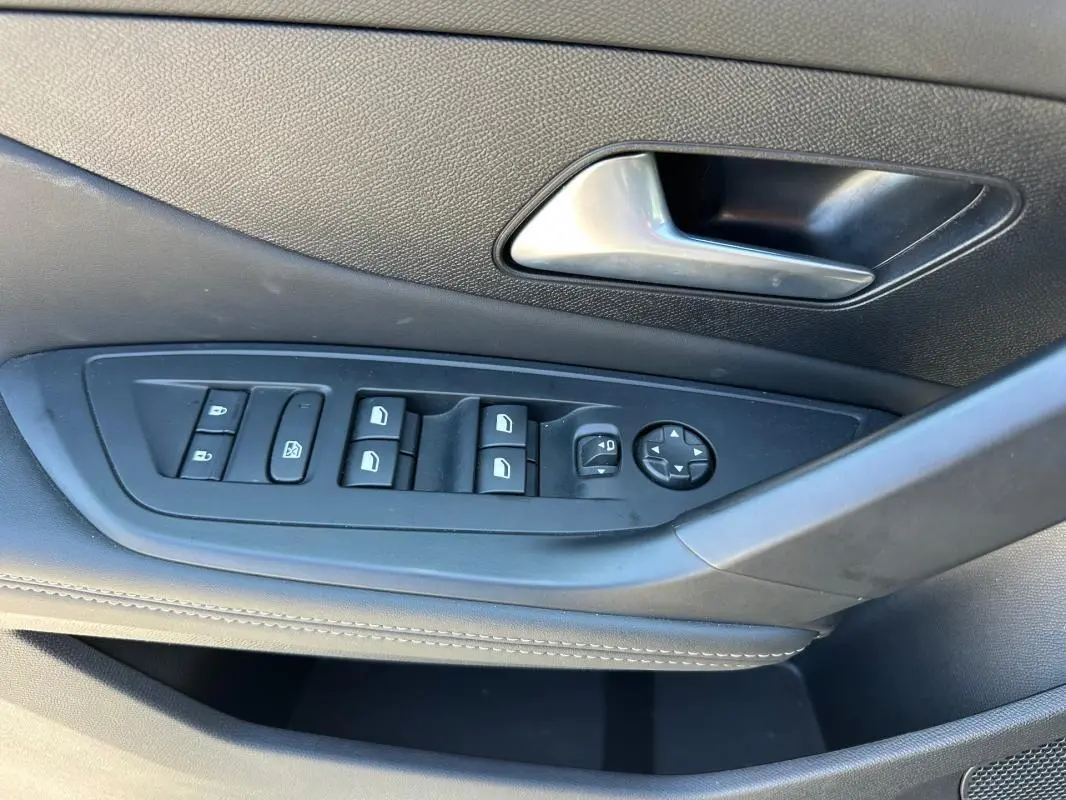 Détail de la porte côté conducteur de la Peugeot 308 SW Hybrid noire, montrant les commandes des vitres et rétroviseurs.