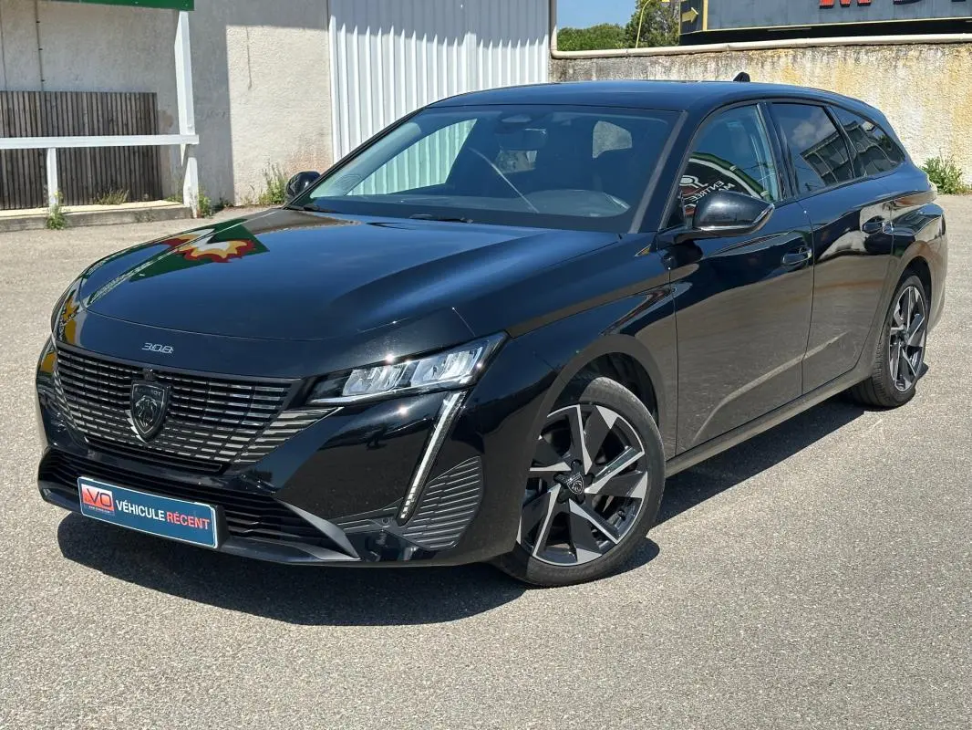 Peugeot 308 SW Hybrid noir vue 3/4 avant droit, avec jantes alliage 17 pouces et calandre distinctive.
