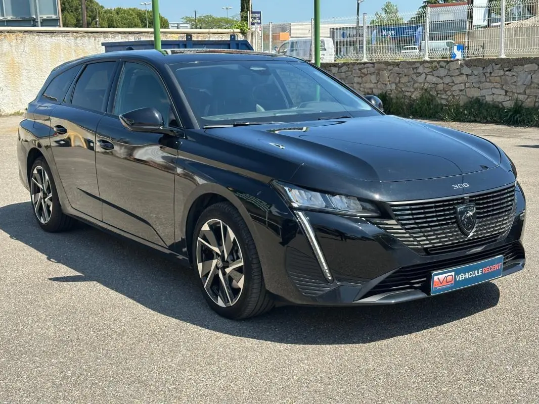 Peugeot 308 SW Hybrid noir vue 3/4 avant droit, avec jantes alliage 17 pouces et calandre distinctive.