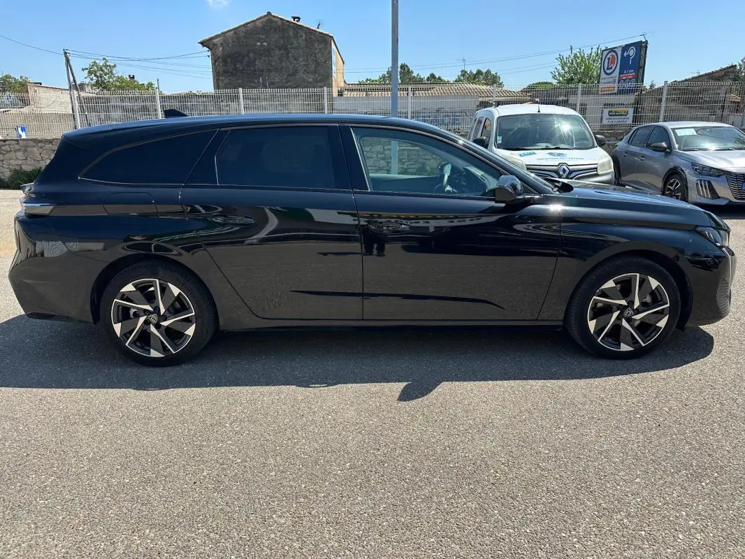 Peugeot 308 SW Hybrid noir vue de profil côté gauche, avec jantes alliage 17 pouces et vitres teintées.