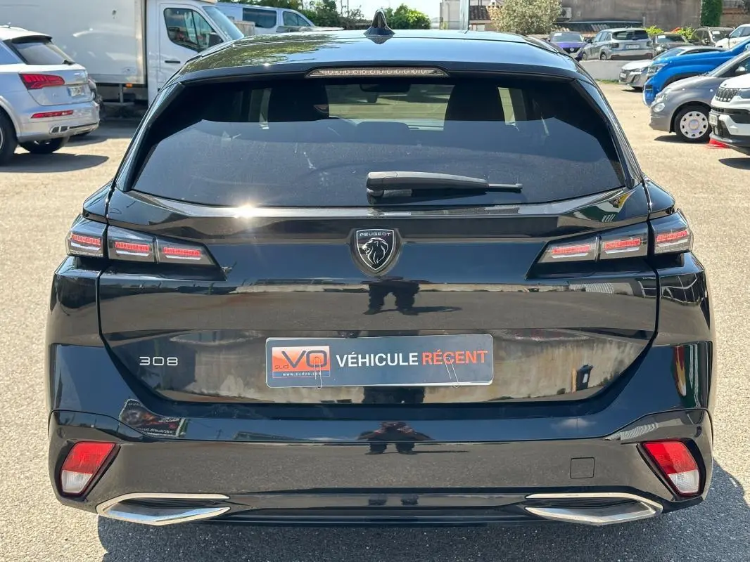 Vue arrière d'une Peugeot 308 SW Hybrid noire de 2025, avec feux LED caractéristiques et badge central Peugeot.