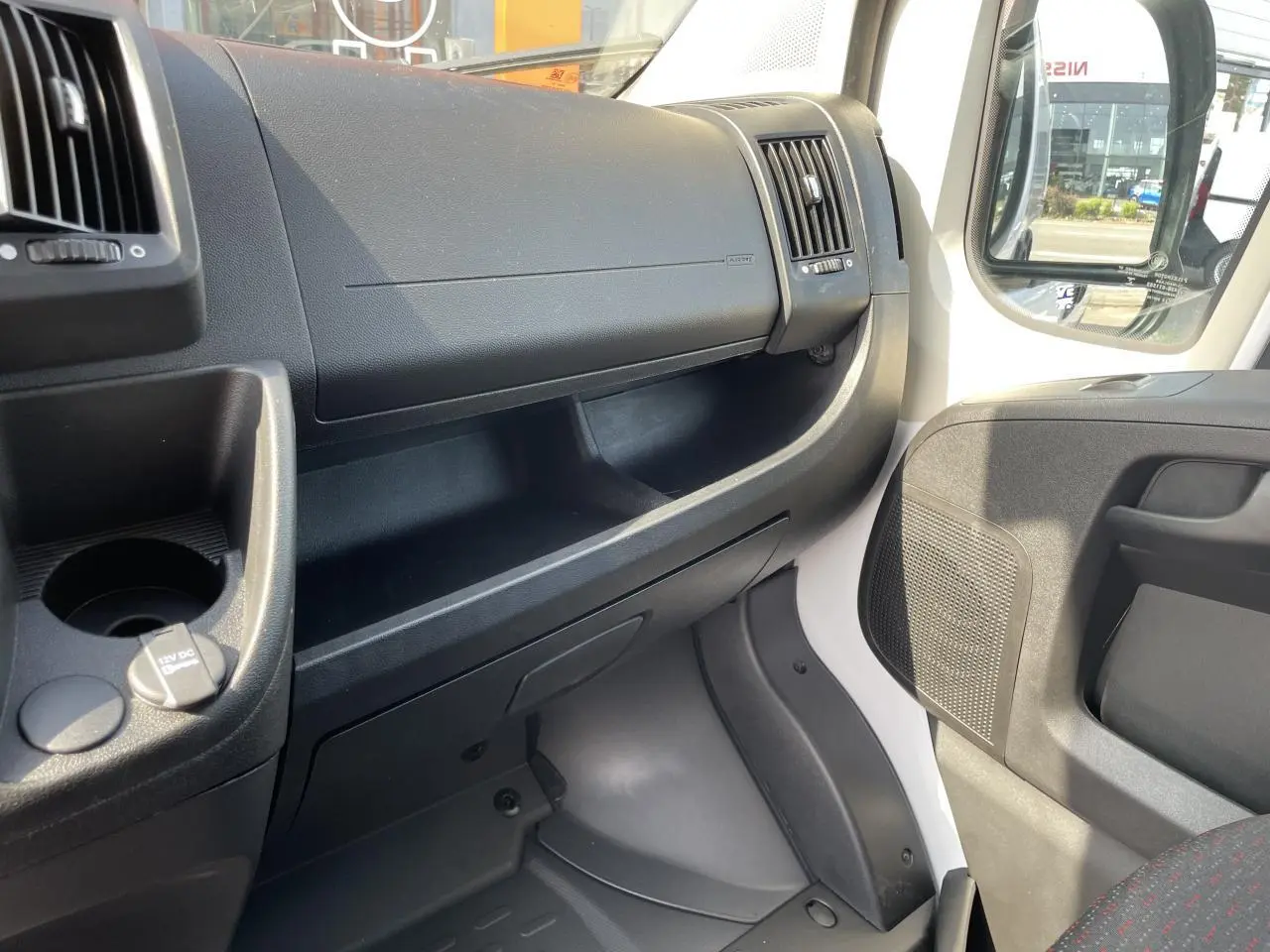 Intérieur côté passager du Peugeot Boxer Fourgon blanc 2023, tableau de bord et porte avec rangement visible.