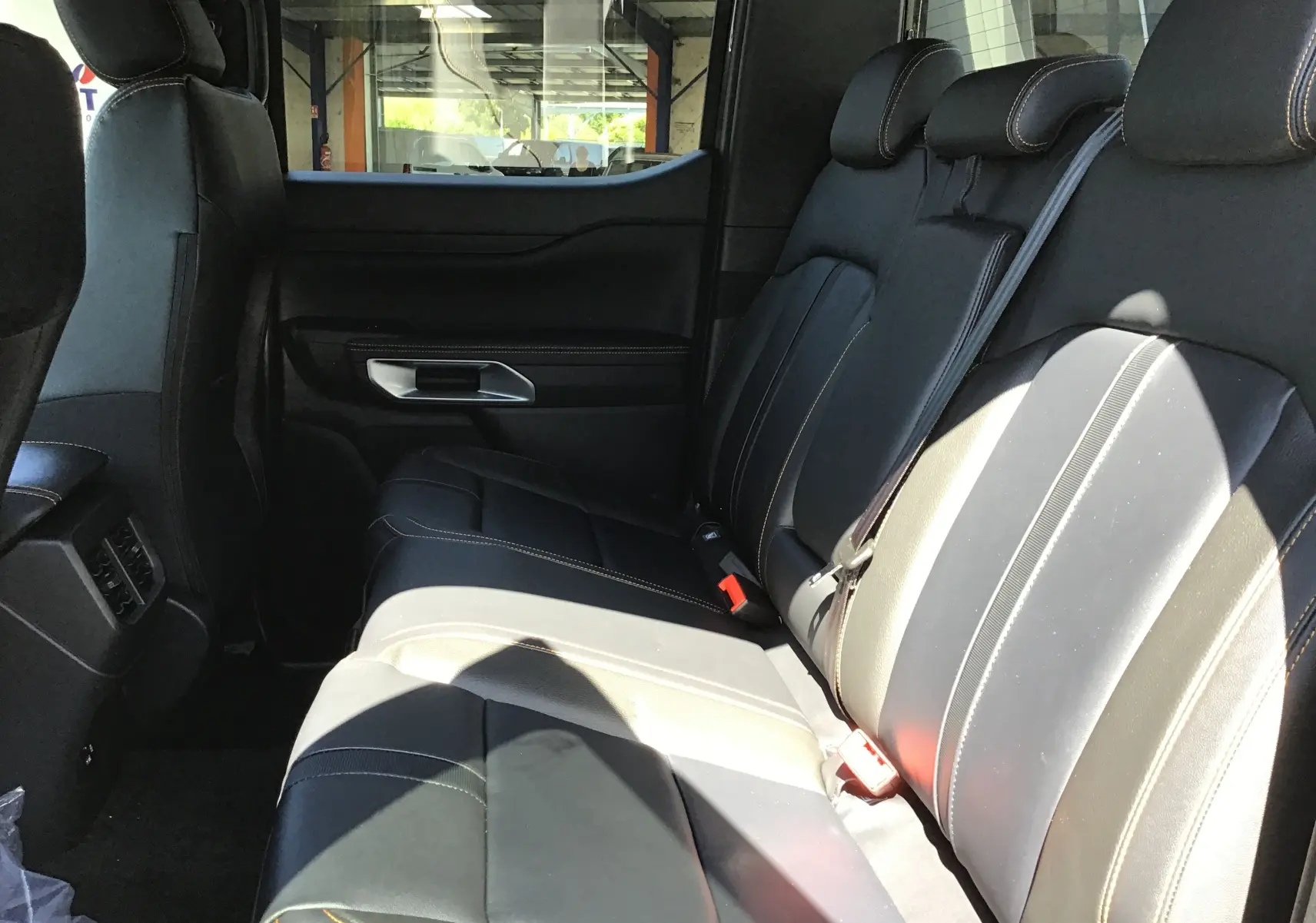 Vue intérieure côté droit des sièges arrière en cuir noir avec surpiqûres contrastantes du Ford Ranger Double Cabine 2025.