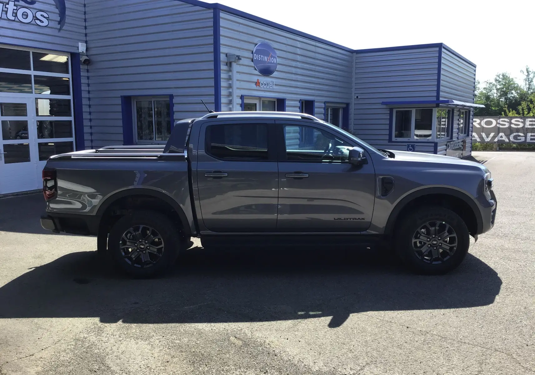 Ford Ranger Double Cabine gris carbone vu de profil côté gauche avec rideau de plateau coulissant et jantes noires.